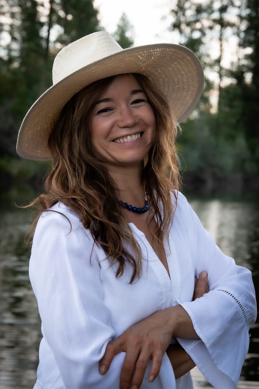 Laura, founder of Thyme and Shine Cleaning, smiling in a straw hat beside the river